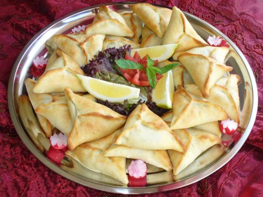 Dreieckige Fatahje-Teigtaschen mit Spinatfüllung, frisch gebacken.
