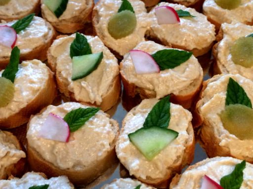 Samtiger veganer Hummus-Kichererbsen-Dip, stilvoll auf gerösteten Baguettescheiben als orientalisches Canapé präsentiert.