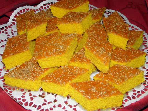 Goldgelber veganer Sfouf-Grießkuchen mit Kurkuma, in Stücke geschnitten und bestreut, als orientalisches Dessert.
