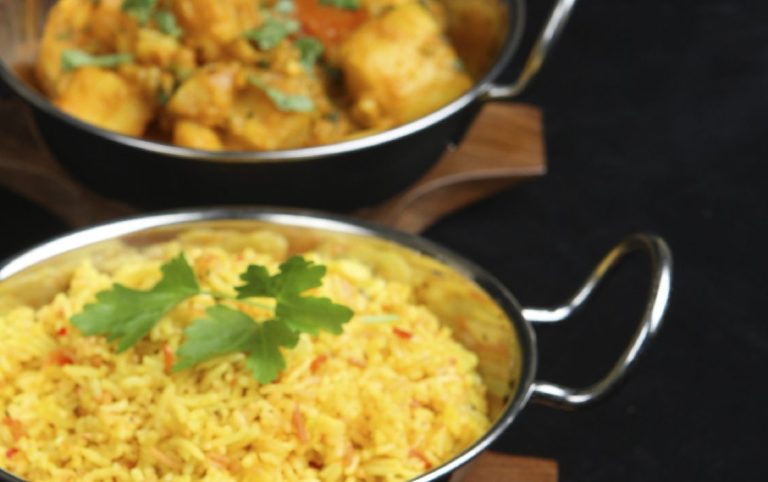 Hochzeit-Catering Berlin mit drei Schalen mit indischen Gerichten: Reis, Curry und Hühnchen, garniert mit Koriander.