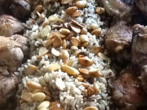 Großer Teller mit gegrilltem Geflügel und aromatischem Reis, typisch arabisch angerichtet.