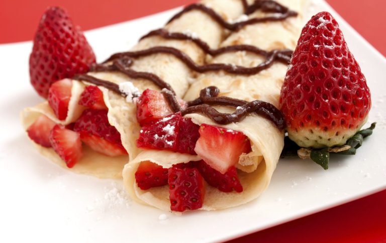 Arabische Desserts-Catering mit Erdbeeren, gefüllt in Crêpes und garniert mit Schokoladensauce.