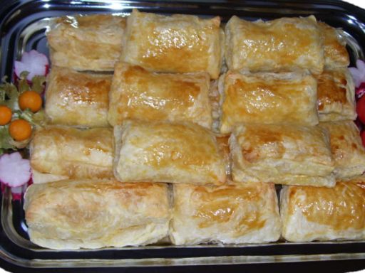 Goldbraune Blätterteigtaschen mit cremiger Käsefüllung, serviert als vegetarische Beilage.