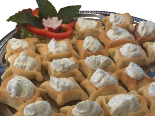 Kleine eckige Teigtaschen (Swiha) mit herzhafter vegetarischer Füllung, als Hauptspeise serviert.