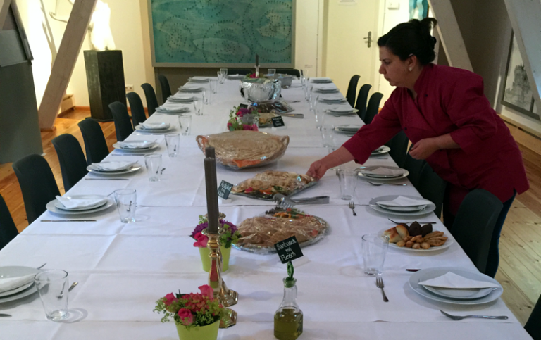 Libanesisches Hochzeitscatering: Eine gedeckte Tafel mit Essen, während eine Person Gerichte anrichtet.