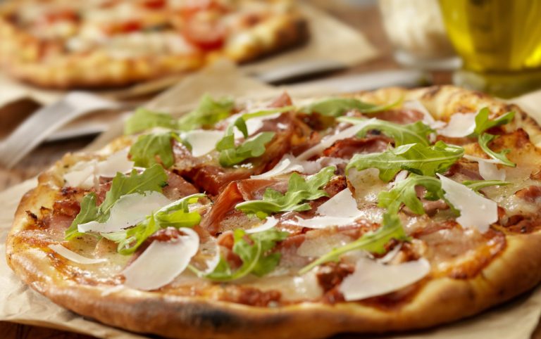 Orientalisches Buffet Berlin mit Pizza mit Tomaten, Käse, Schinken und frischem Rucola.