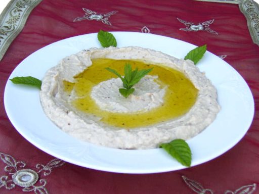 Teller mit cremigem Mutabal (Auberginencreme), garniert mit Minze und Olivenöl.