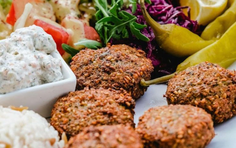 Appetitliche Collage mit vegetarischen Falafeln, Dips, Reis und frischen Salaten von Al-Layal Catering Berlin.