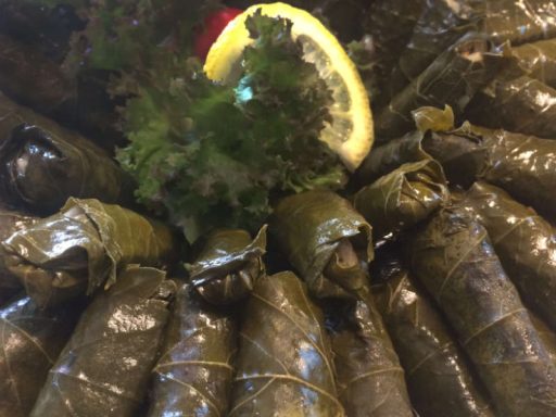 Gerollte Weinblätter mit aromatischer veganer Reisfüllung, ansprechend auf einer Platte serviert, als Hauptspeise-Komponente oder Beilage.