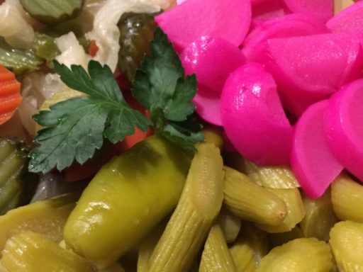 Buntes eingelegtes Gemüse wie Gurken, Rüben und Paprika, appetitlich angerichtet, als würzige vegane Beilage.