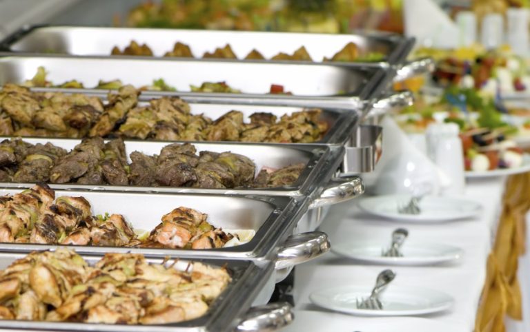 Private Feier Catering: Buffet mit verschiedenen Fleischgerichten und Salaten in Warmhaltebehältern.